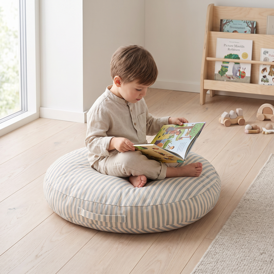 Child sitting on the blue striped floor cushion reading a picture book