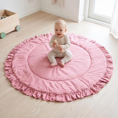 Baby sitting and playing on the round rose ruffle playmat
