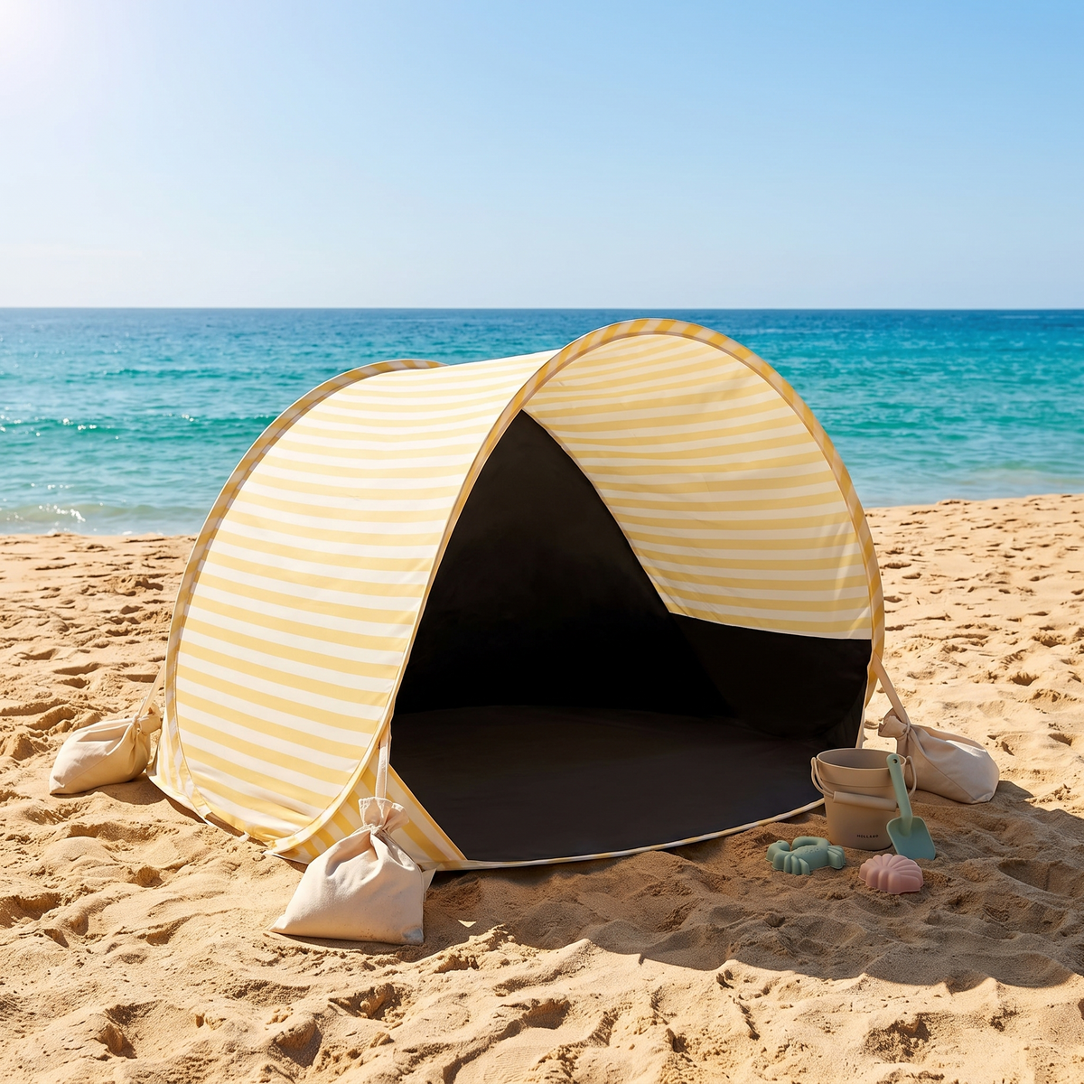 Kids pop-up beach tent anchored with sandbags on a sunny Australian beach with sand toys
