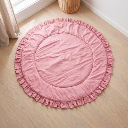 Round rose pink quilted cotton playmat with ruffle border on the floor of a bright nursery