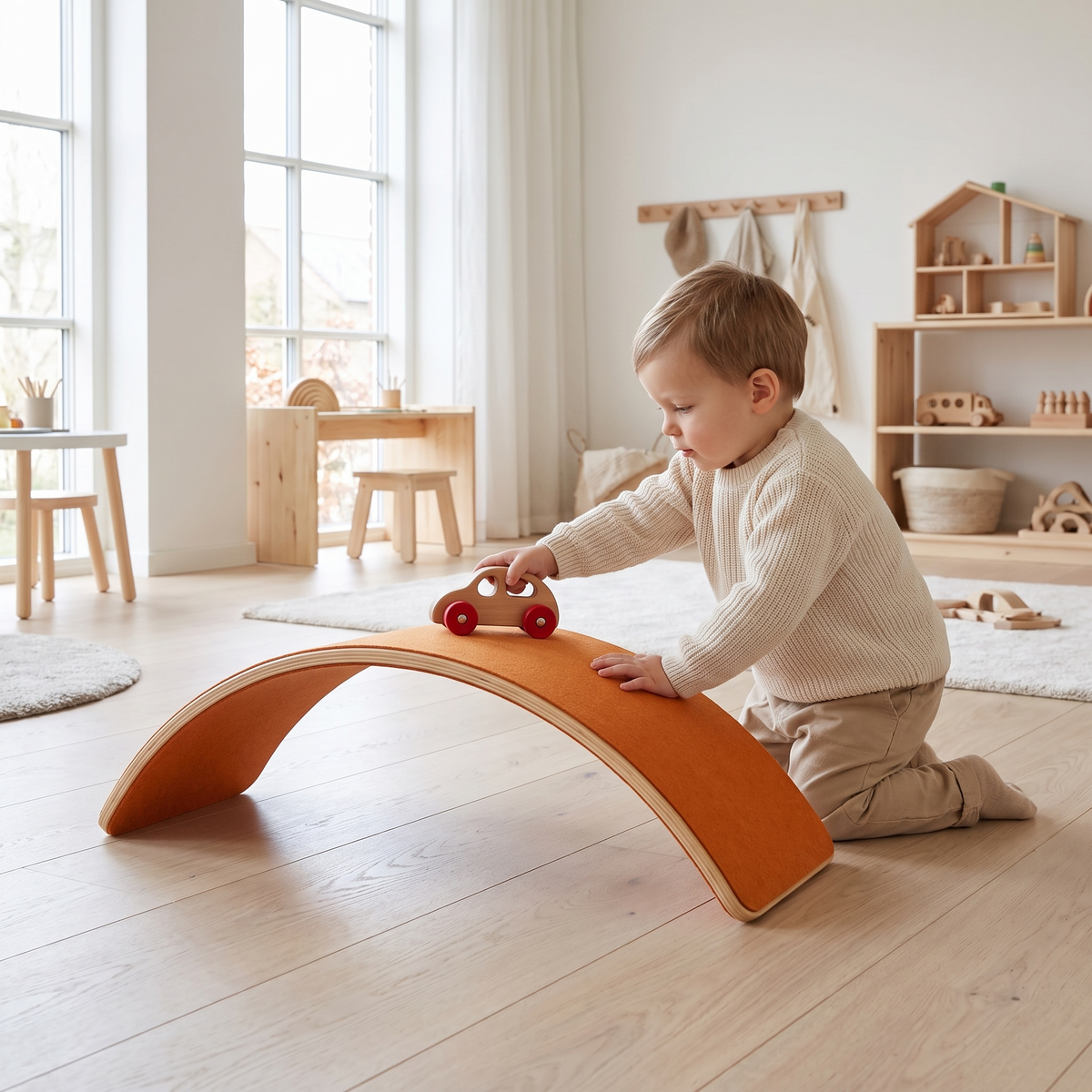 Toddler using the wooden balance board as a bridge for a toy car