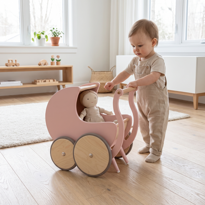 Toddler pushing the wooden doll pram walker with a rag doll inside