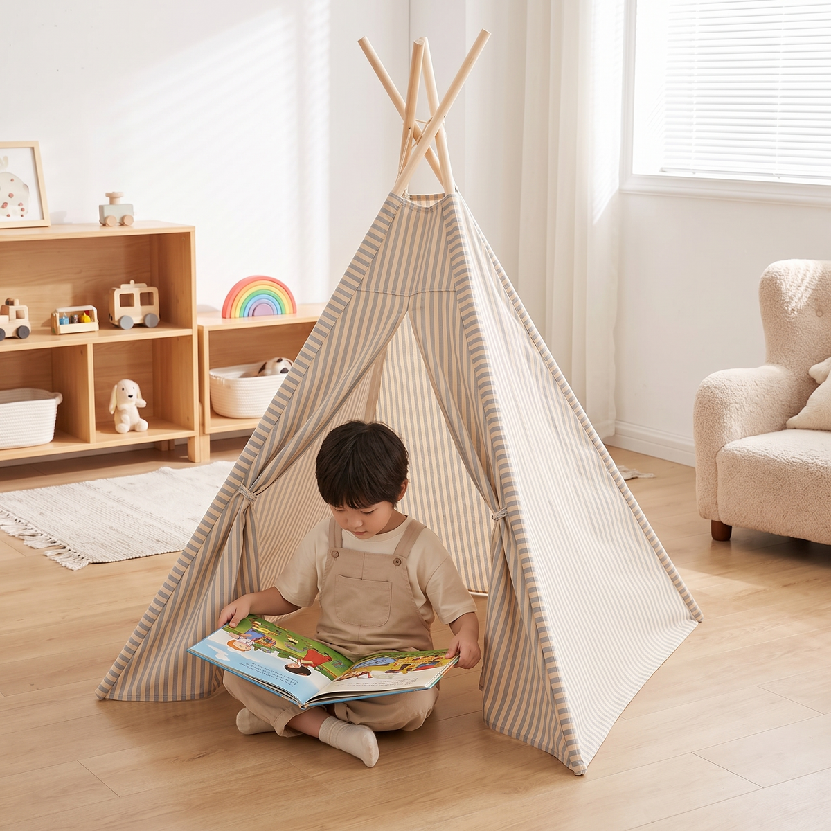 Child reading a picture book in the doorway of the blue striped teepee