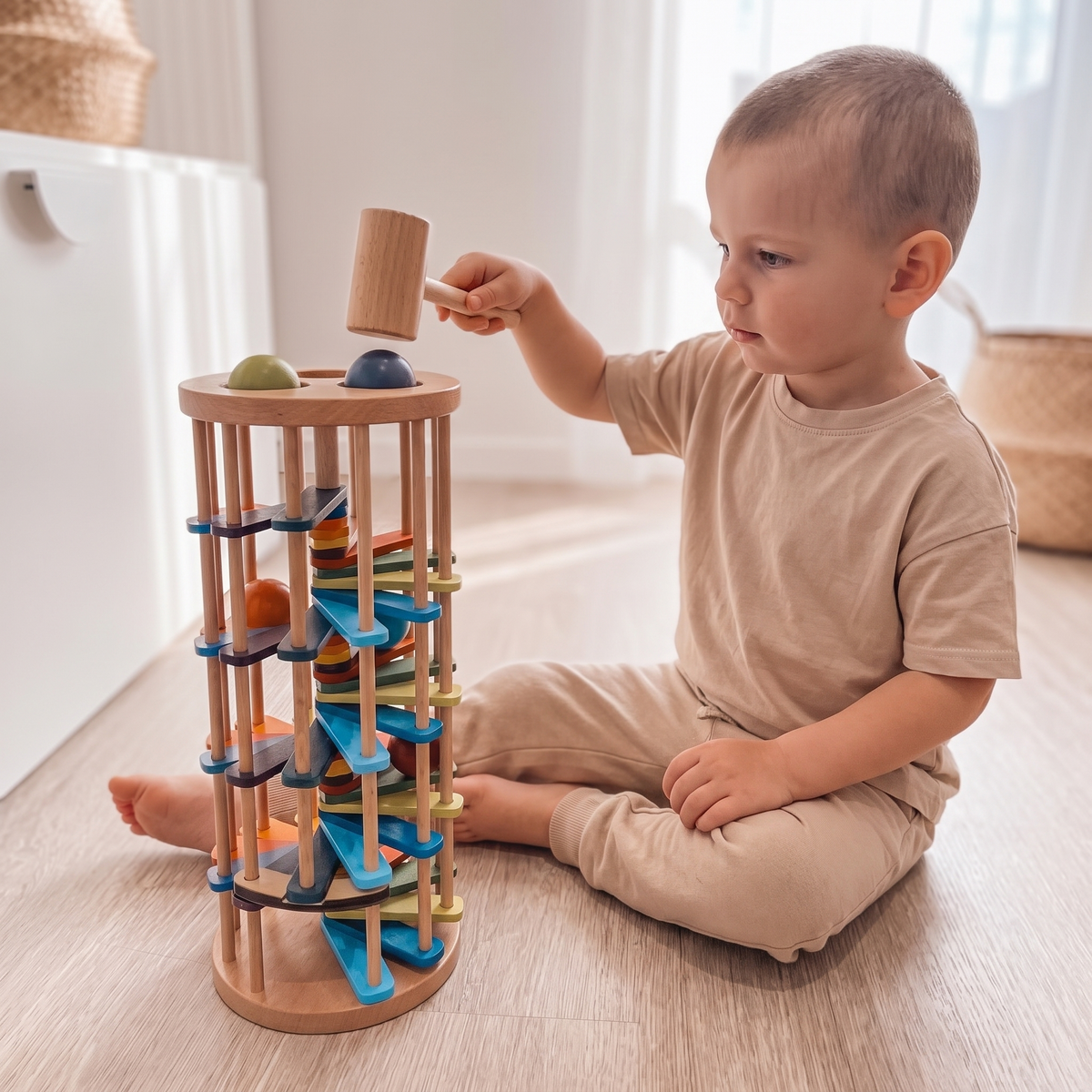 Child tapping a ball into the wooden tap and roll tower with the hammer