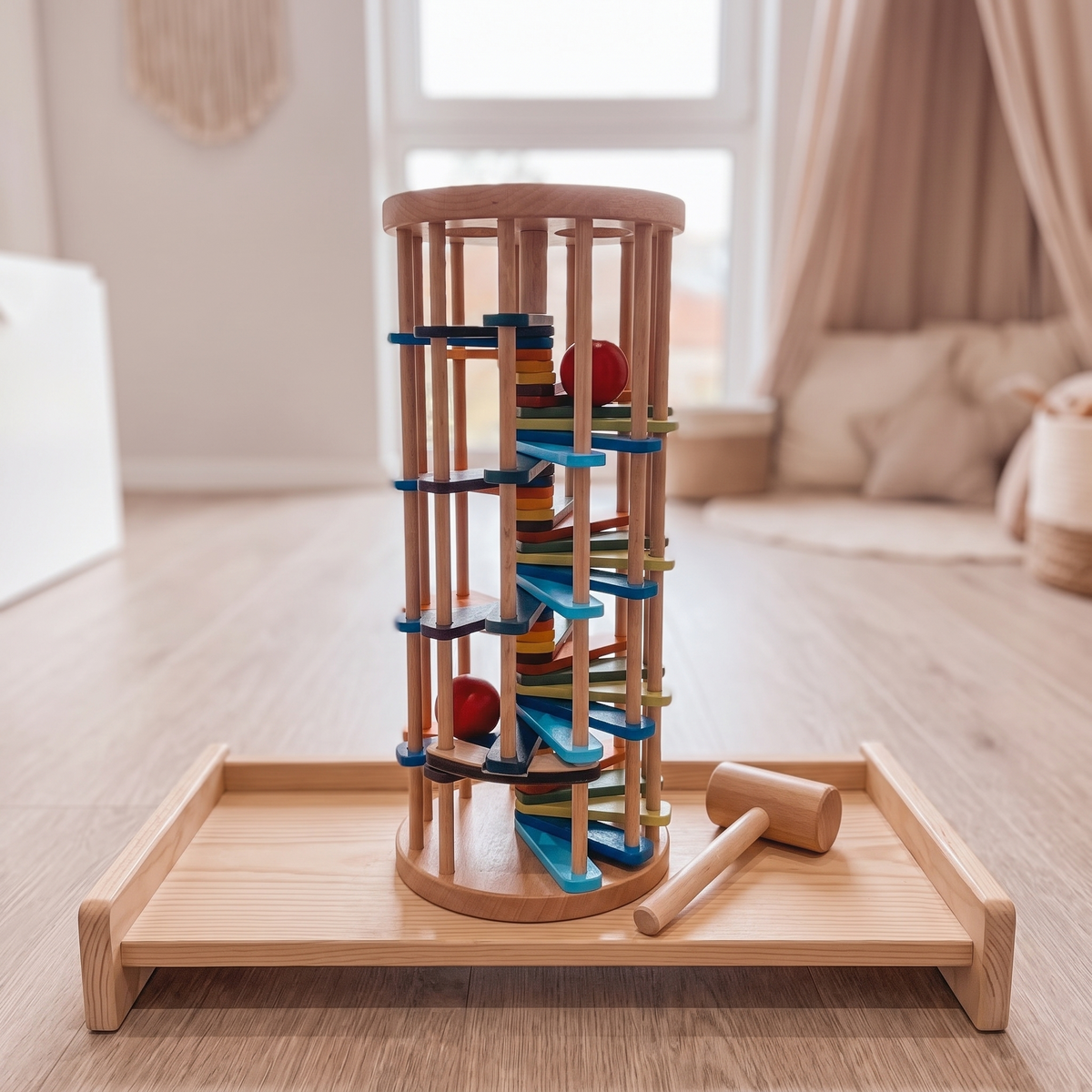 Wooden tap and roll ball tower on a playroom shelf with a ball rolling down the spiral