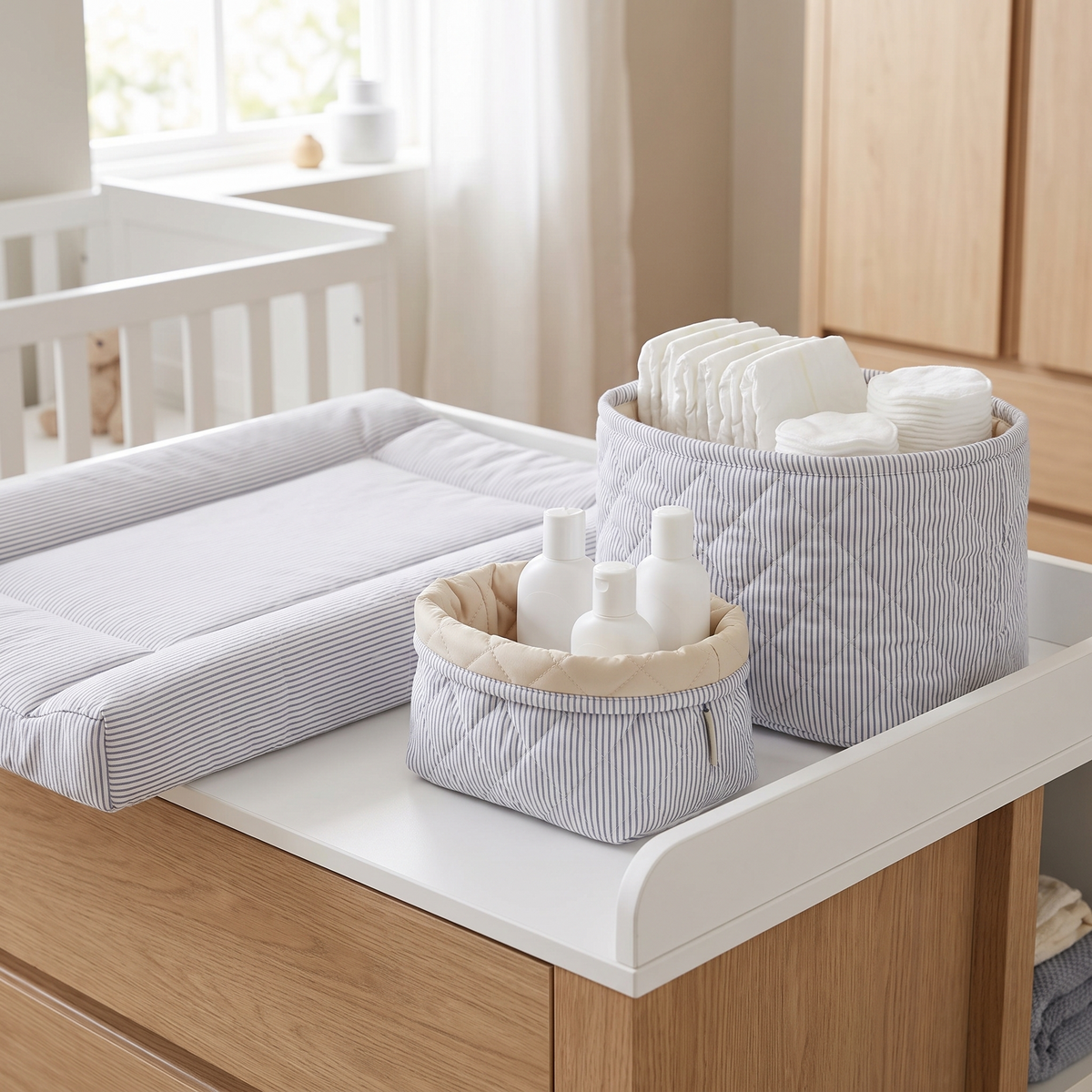 Quilted storage baskets stocked with nappies and essentials on a change table