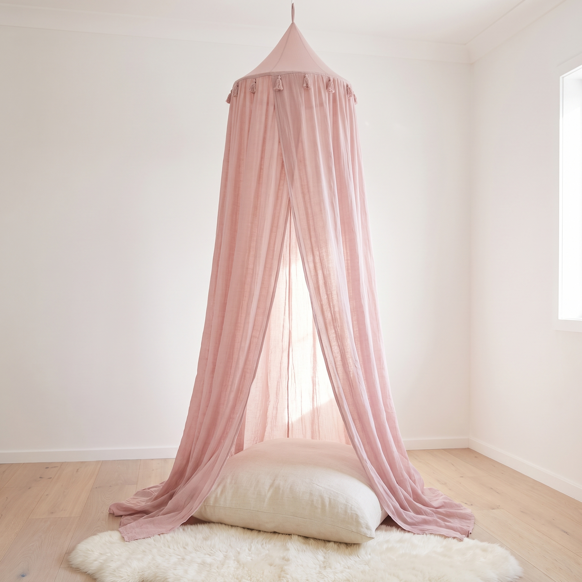 Dusty pink sheer hanging bed canopy in a bright kids bedroom