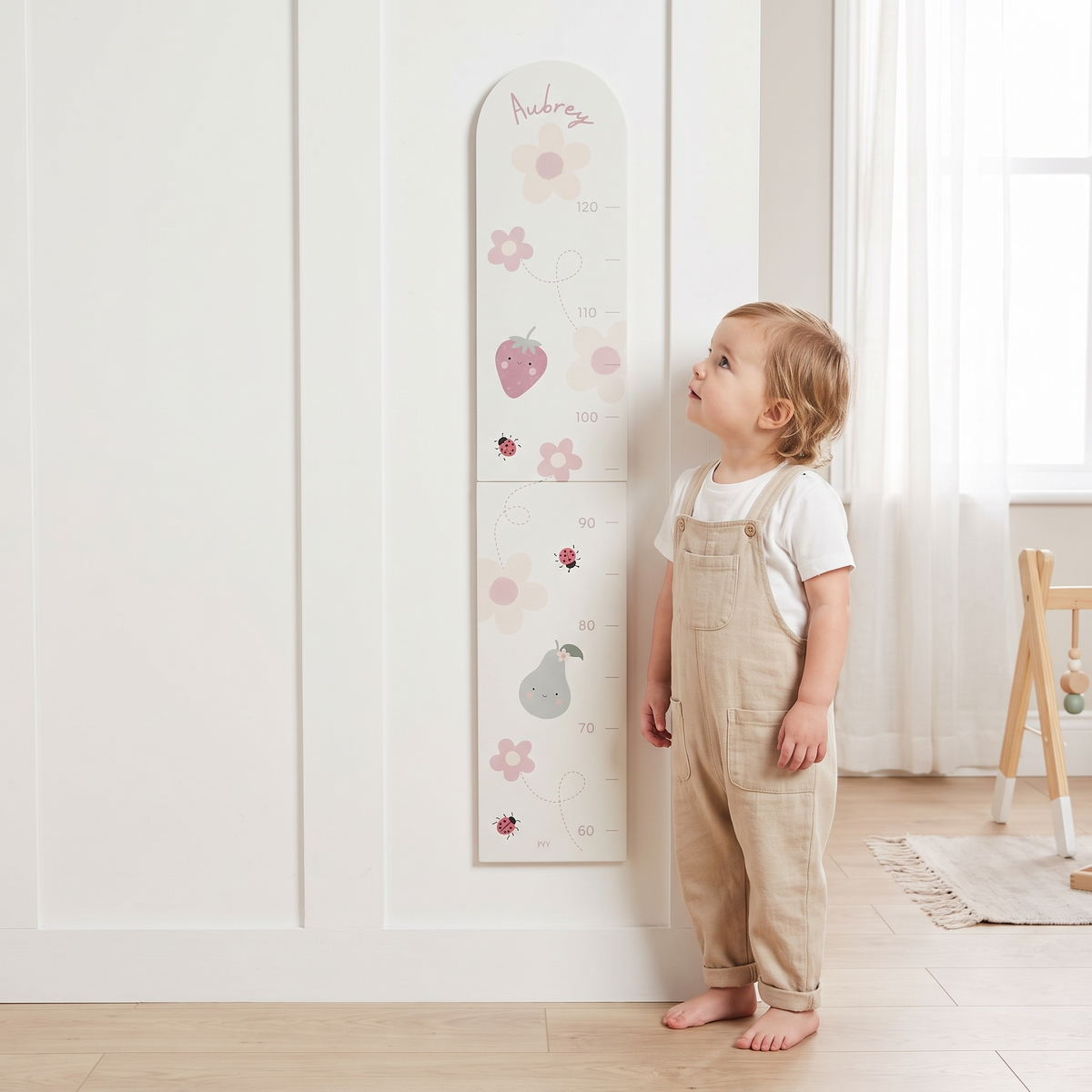 Close-up of bloom and blossom illustrations and child's name on wooden height chart