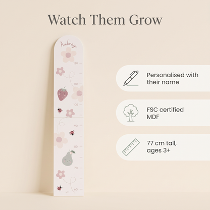 Child being measured against a personalised bloom and blossom wooden growth chart