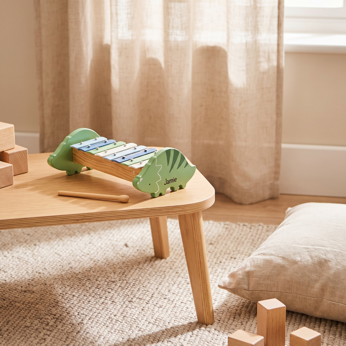 Dinosaur xylophone with metal keys and wooden beater on a playmat