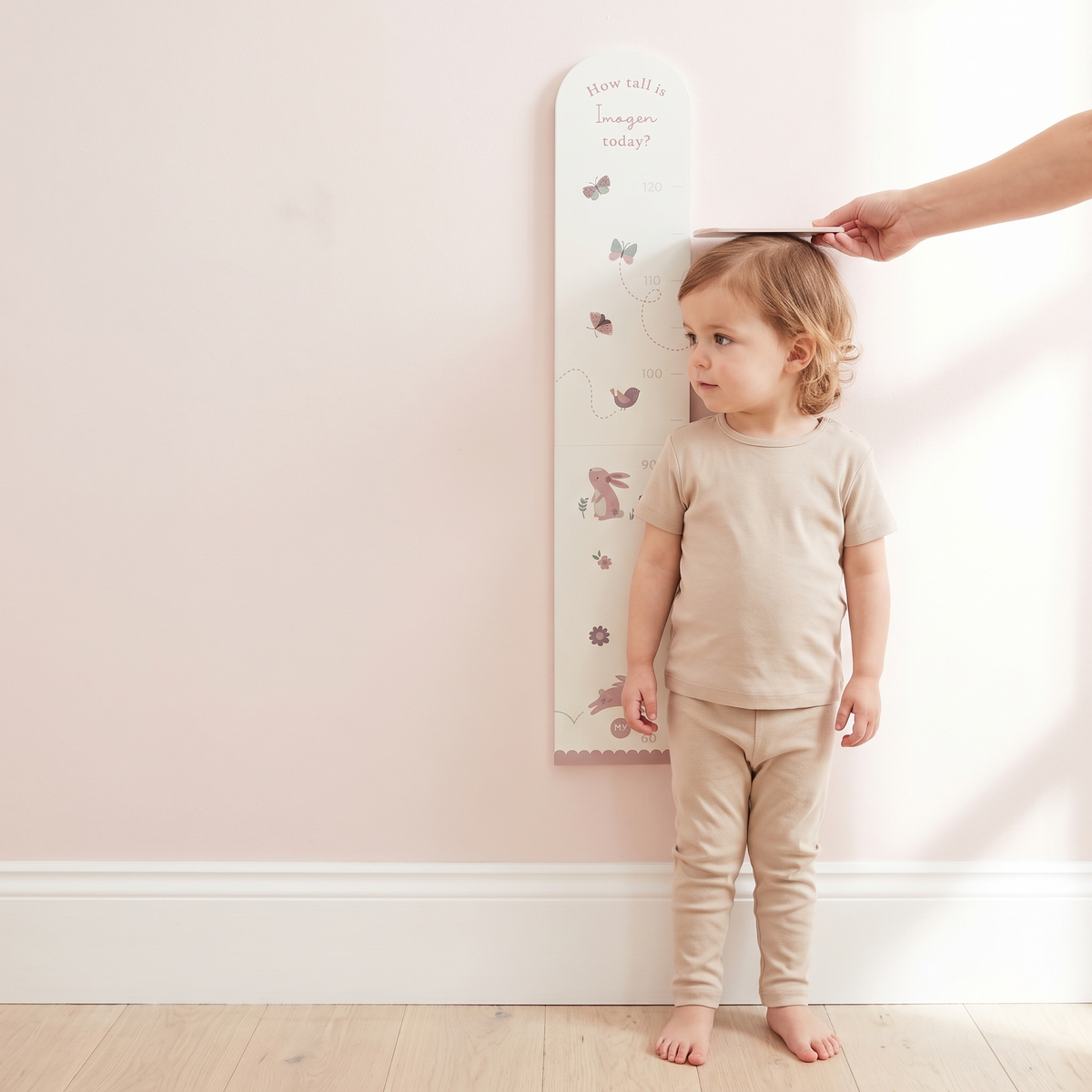 Woodland height chart mounted on a nursery wall beside a cot