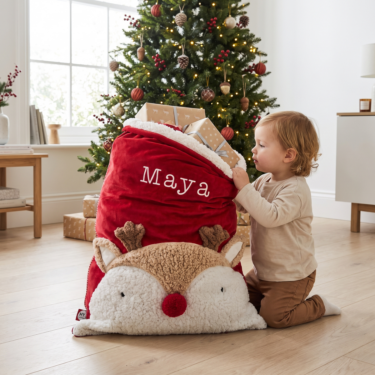 Reindeer Santa sack with personalised name beside a Christmas tree
