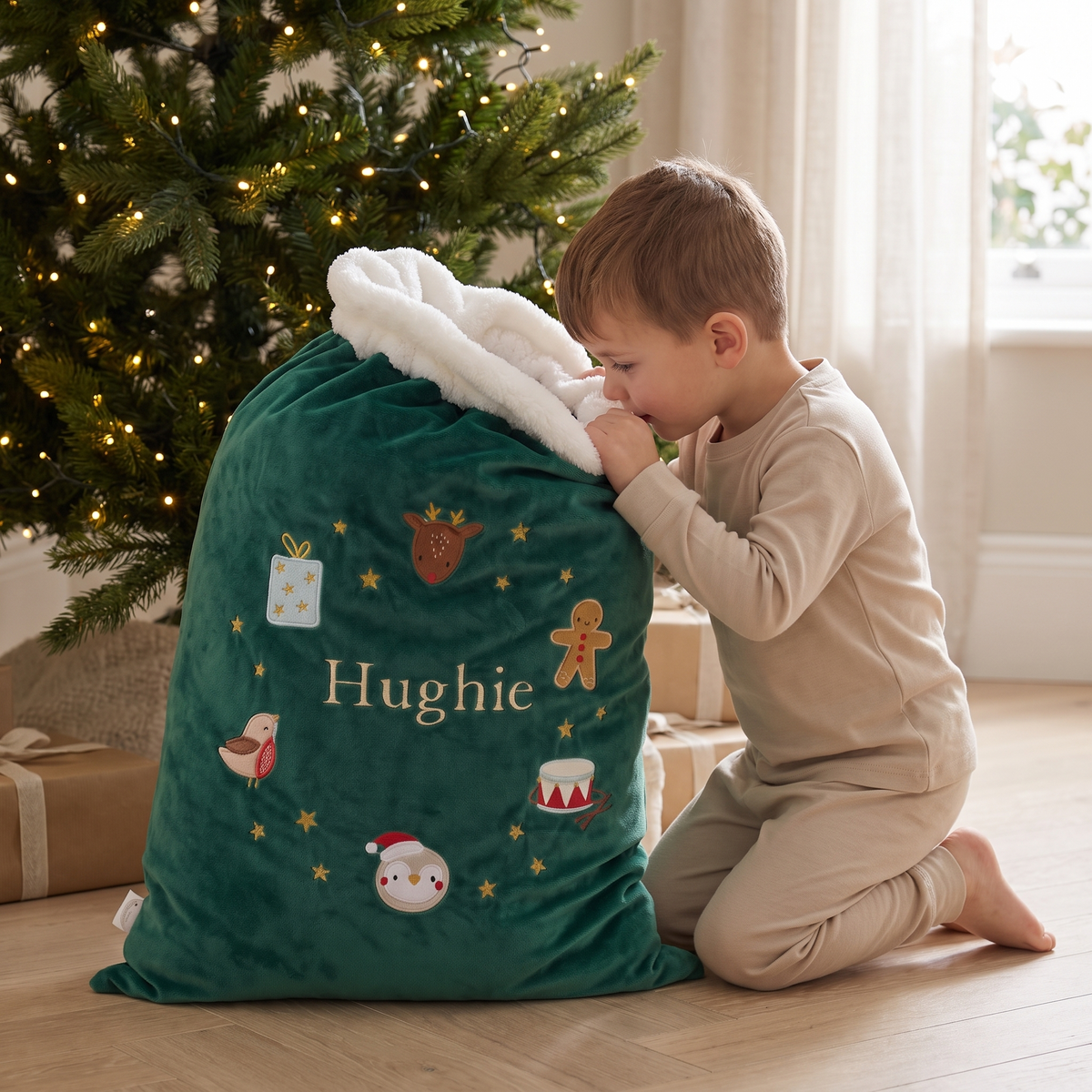 Green embroidered wreath Santa sack beside a decorated Christmas tree