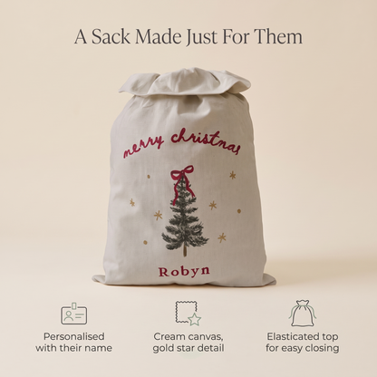 Child with a personalised cream canvas Santa sack on Christmas morning