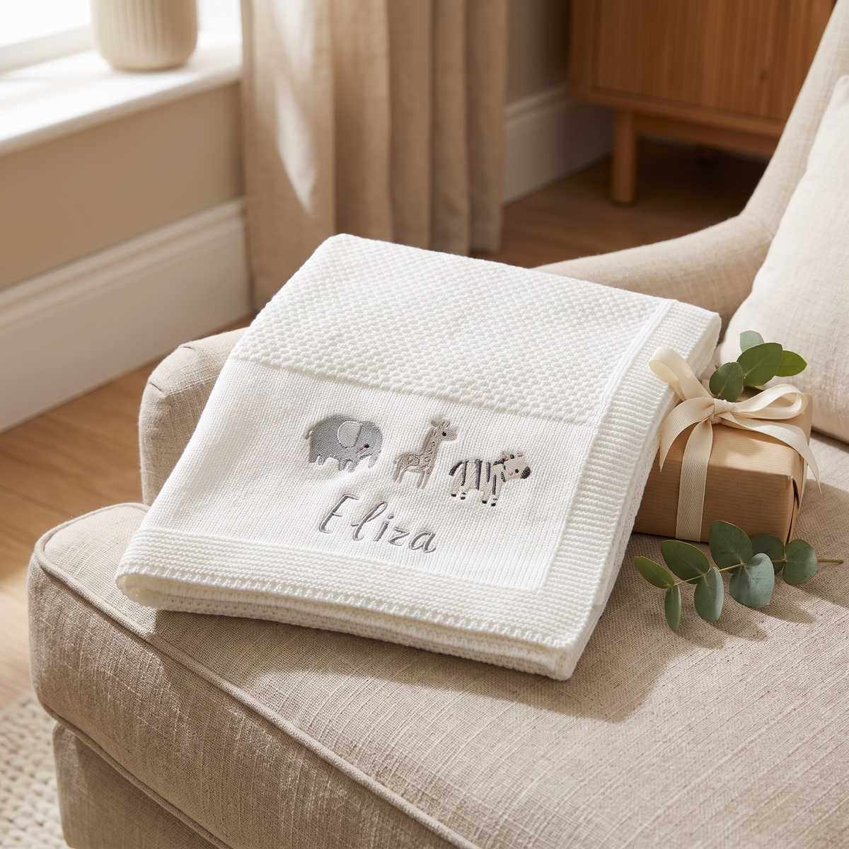 Ivory baby shawl blanket draped over a cot in a soft neutral nursery