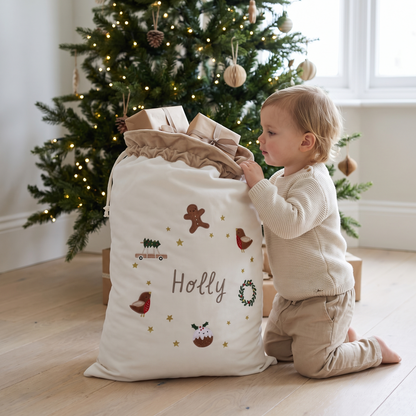 Cream personalised Santa sack under a Christmas tree in a neutral living room