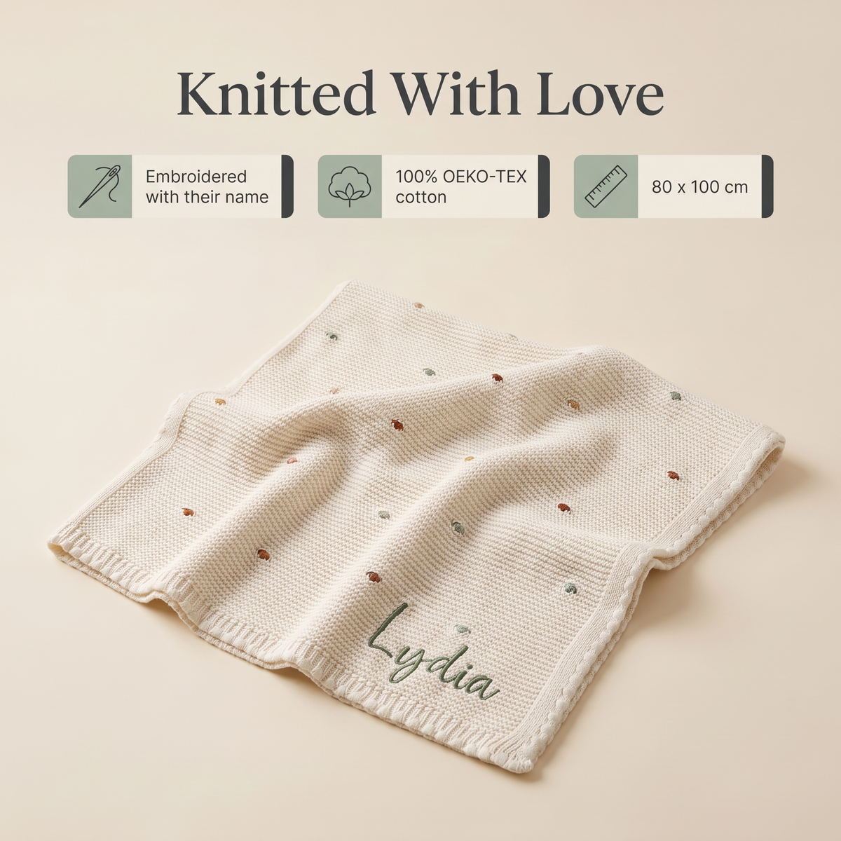 Baby lying on a personalised knitted bobble blanket with cream edging
