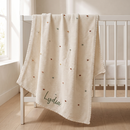 Personalised multi-colour bobble knitted baby blanket with embroidered name on a cot