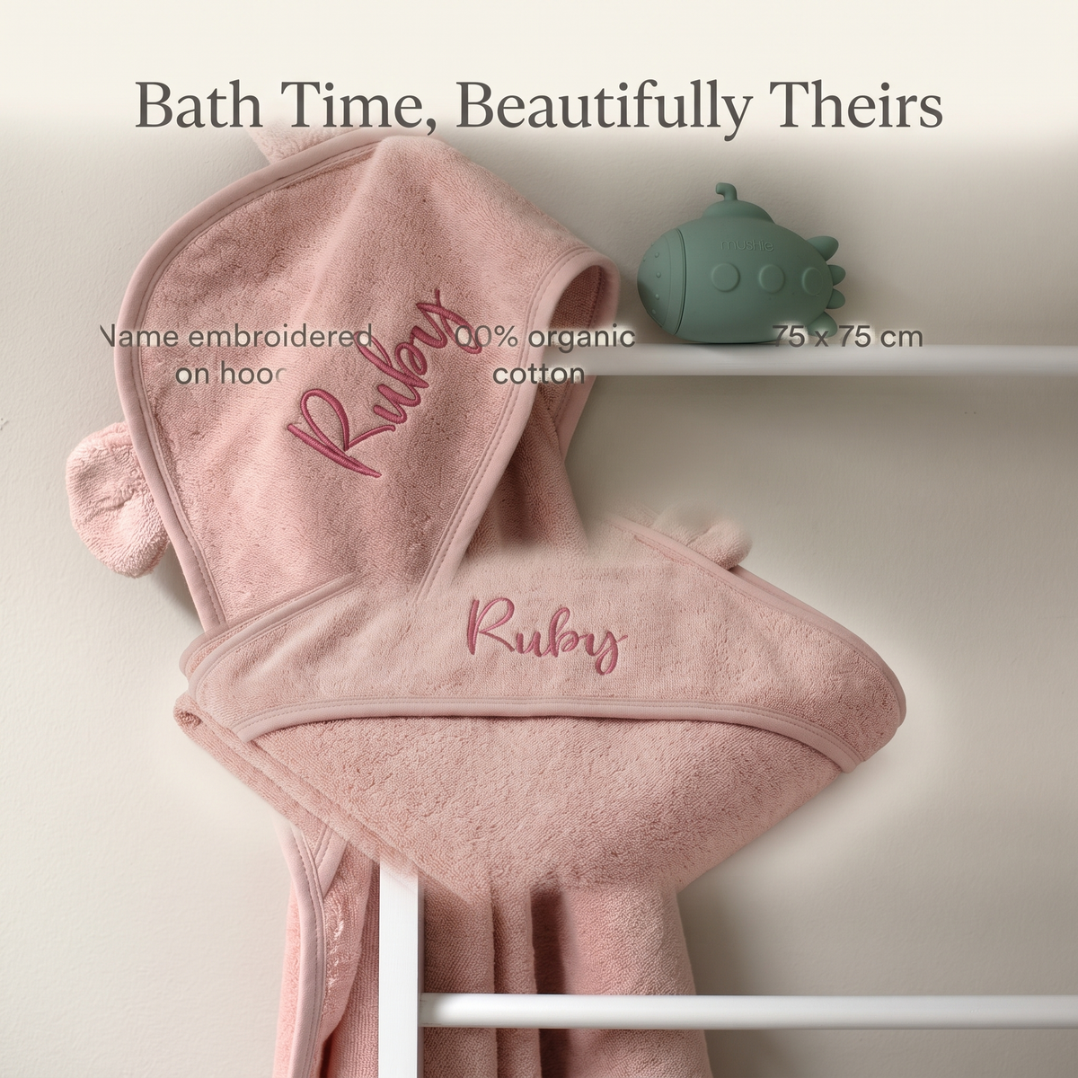 Baby wrapped in a personalised dusky pink hooded towel after bath time