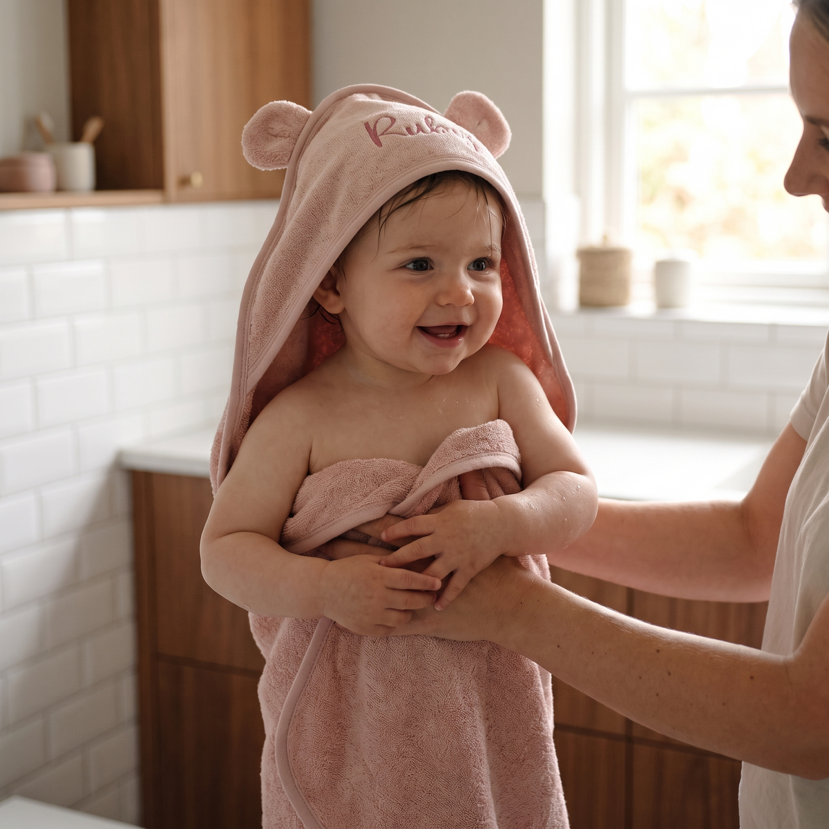 Close-up of embroidered name on hood of dusky pink baby towel