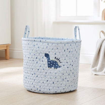 Personalised blue quilted dinosaur storage bag with embroidered name in a playroom
