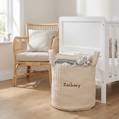 Large neutral storage bag filled with toys beside a child's bed
