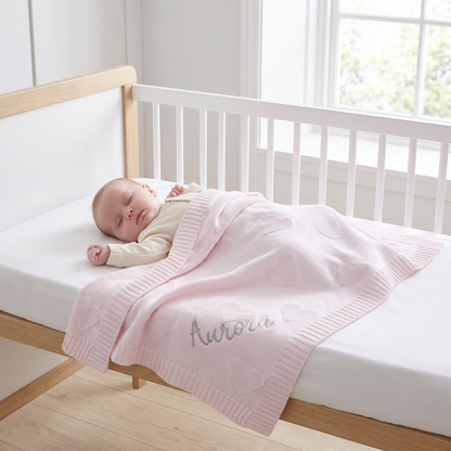 Close-up of woven heart pattern and silver embroidery on pink cotton baby blanket