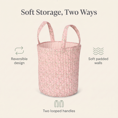 Pink storage basket holding blankets and books on a nursery floor