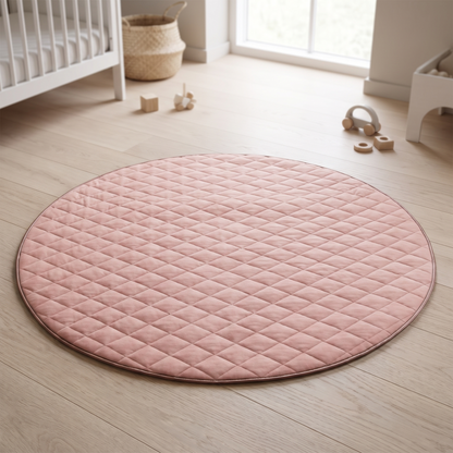 Dusty pink round quilted cotton baby play mat on a nursery floor