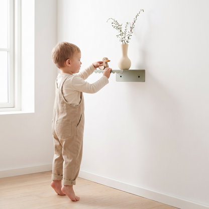 Green steel wall shelf styled with picture books and a small toy
