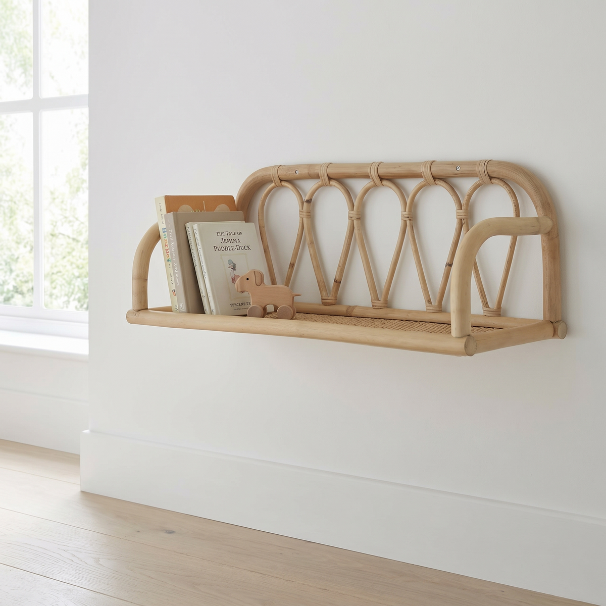 Small natural rattan wall shelf mounted in a nursery with books and toys