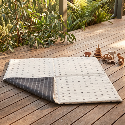 Mudcloth padded play mat set up for tummy time in a bright playroom