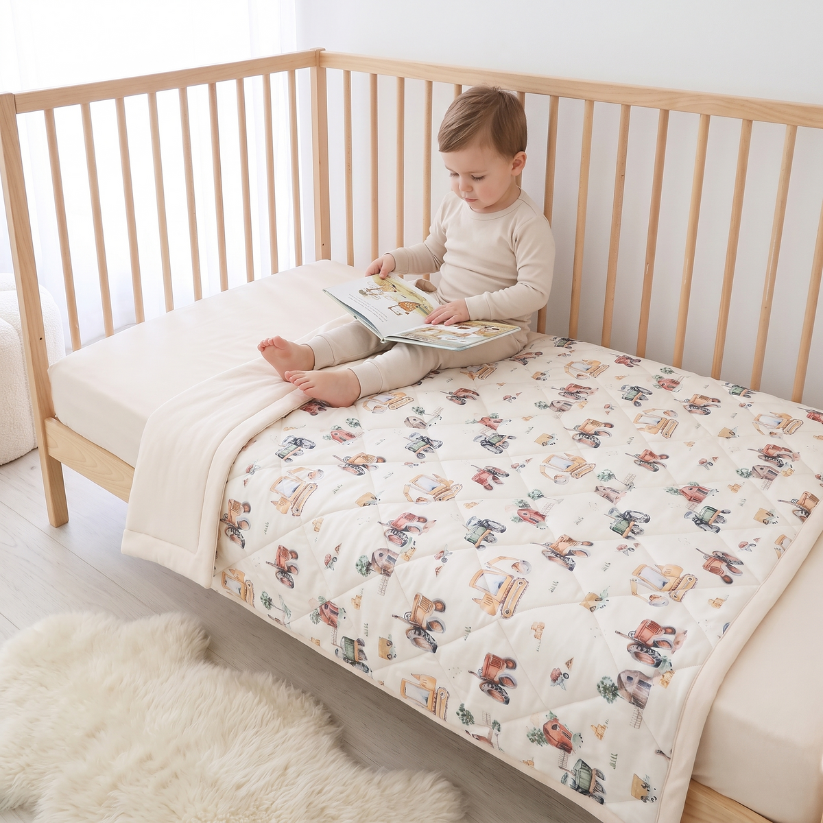 Little Teekie Reversible Quilted Organic Jersey Cot Comforter | 100x120cm – Vehicles Print – in use, shows scale
