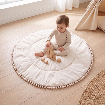 Little Teekie Quilted Cotton Round Play Mat | Pom-Pom Trim 110cm – Oat – in use, shows scale